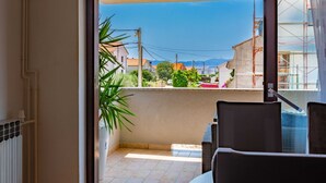 A balcony with a view of a residential area, including houses and mountains in the distance. - Three Bedroom Apartment with Private Pool (Zadar)