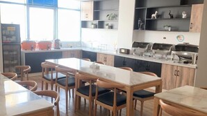 Una cocina moderna con armarios de madera, encimera de mármol y una zona de estar con mesas y sillas de madera.