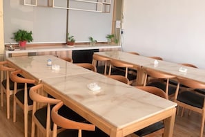 A conference room with multiple tables and chairs, a whiteboard, and potted plants.