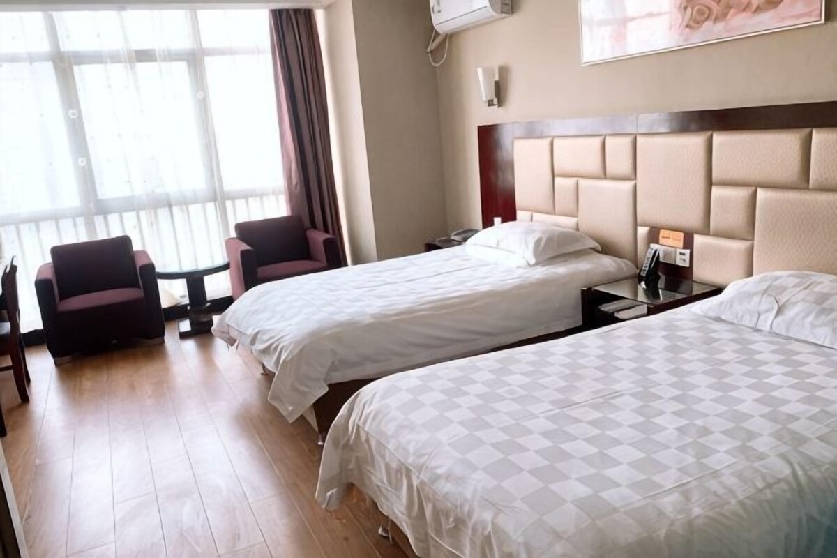 Ein Hotelzimmer mit zwei Betten, einem Schreibtisch und einem Stuhl.