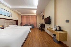 Habitación de hotel con dos camas, un escritorio, una silla, un televisor y un minibar.