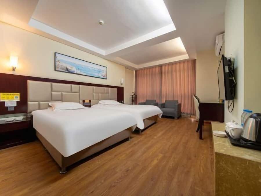 Una habitación de hotel con dos camas, un escritorio, una silla, un televisor y una cafetera.
