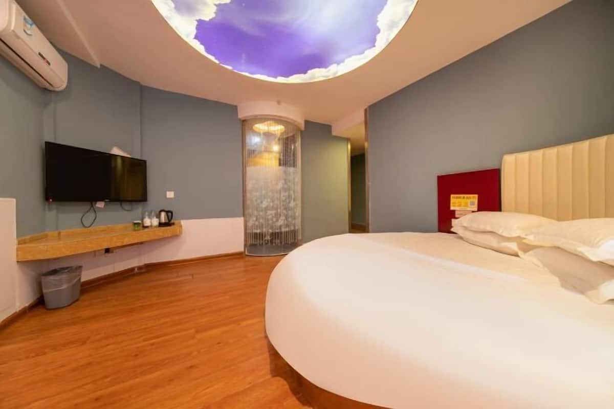 A hotel room with a large bed, a flat-screen TV, a wooden floor, and a unique ceiling feature.