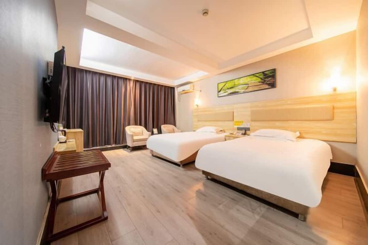 A hotel room with two beds, a desk, a chair, a TV, and a painting on the wall.