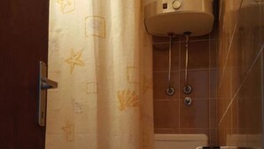 Un baño con inodoro, calentador de agua y cortina de ducha.