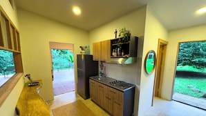 A modern kitchen with wooden cabinets, a built-in gas stove, and a view of the garden through a glass door.