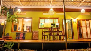 A restaurant with a green wall, wooden furniture, and hanging lights.