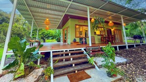 A covered outdoor area with wooden steps leading to a building with a green facade.