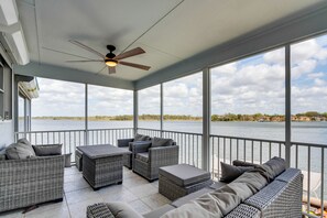 A covered outdoor seating area with wicker furniture and a ceiling fan, overlooking a body of water. - Waterfront Gem w/ Dock in Crystal River! (Crystal River)