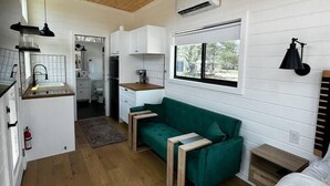Een compacte, moderne woonruimte met een kitchenette, een plafondventilator en een raam dat voor natuurlijk licht zorgt.