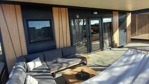 A modern outdoor seating area with a sofa and a coffee table, a sliding glass door, and a star decoration on the wall.