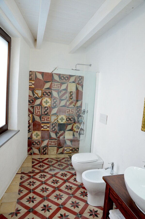 Un baño con baldosas estampadas, un inodoro, un bidé y un lavamanos.