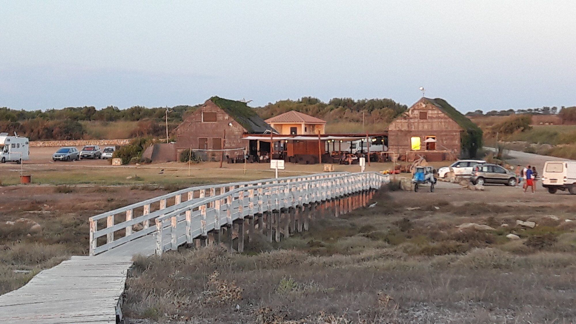 A rustic building with a wooden deck leading to a dock.