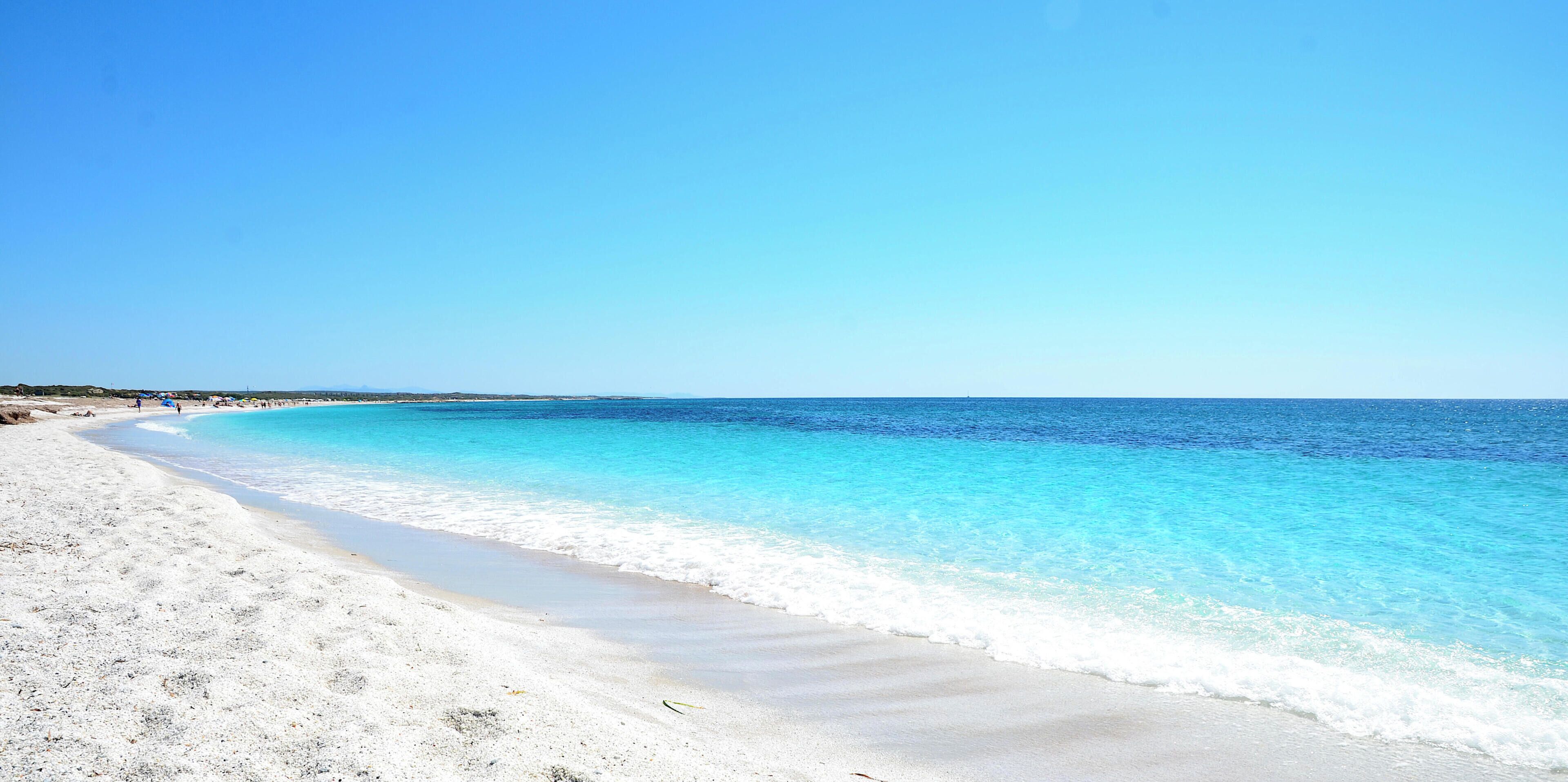 A beach with clear turquoise water and white sand.