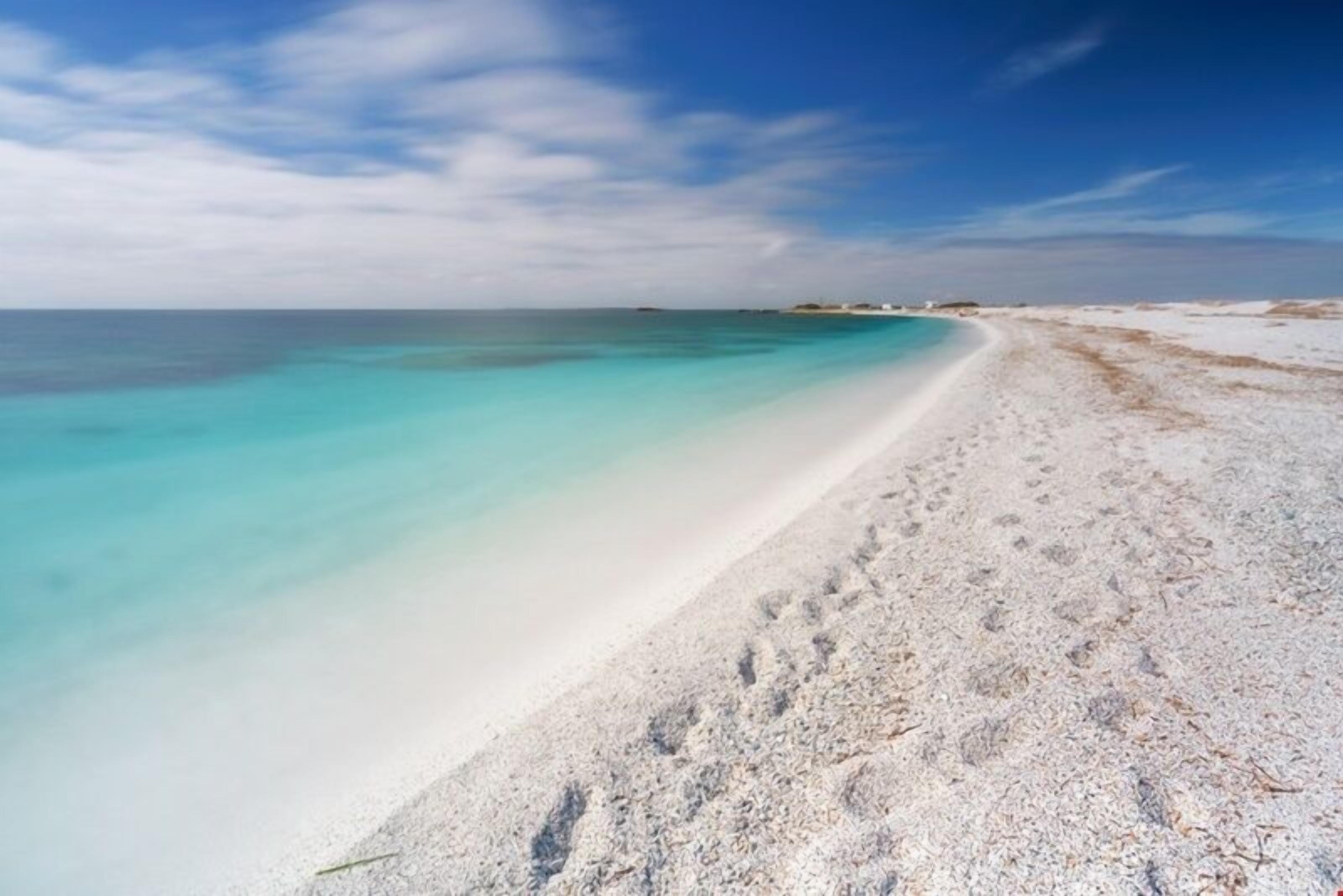 A beach with clear turquoise water and white sand.