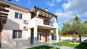 A two-story house with a covered porch, a swimming pool, and a well-maintained lawn. - Apartment Villa Troskot - Villa with pool (Pirovac)