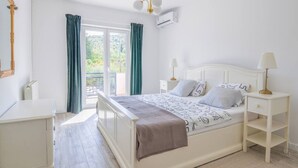 A bedroom with a bed, bedside tables, a dresser, a mirror, and a window with curtains. - Apartment Villa Troskot - Villa with pool (Pirovac)