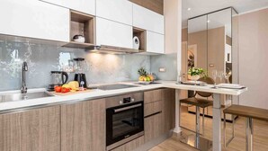 A modern kitchen with a built-in oven, a coffee maker, and a fruit bowl. - Modern Comfort with Shared Pool, Balconies & Lush Green Surroundings - One Bedroom Apartment (Kastav)
