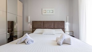 Un hotel moderno con una cama grande, dos mesitas de noche, un espejo y un cuadro enmarcado en la pared.