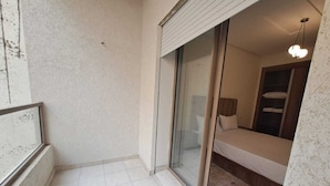 A small, private balcony with a sliding glass door leading to a bedroom.