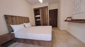 A bedroom with a bed, wooden headboard, bedside table, and a small rug.