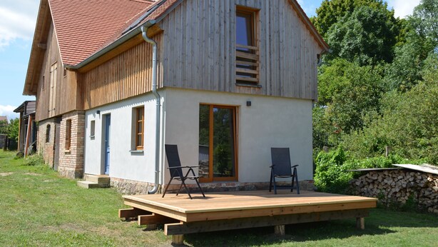 Une maison en bois avec un toit en pente, un porche à l’avant et une terrasse.