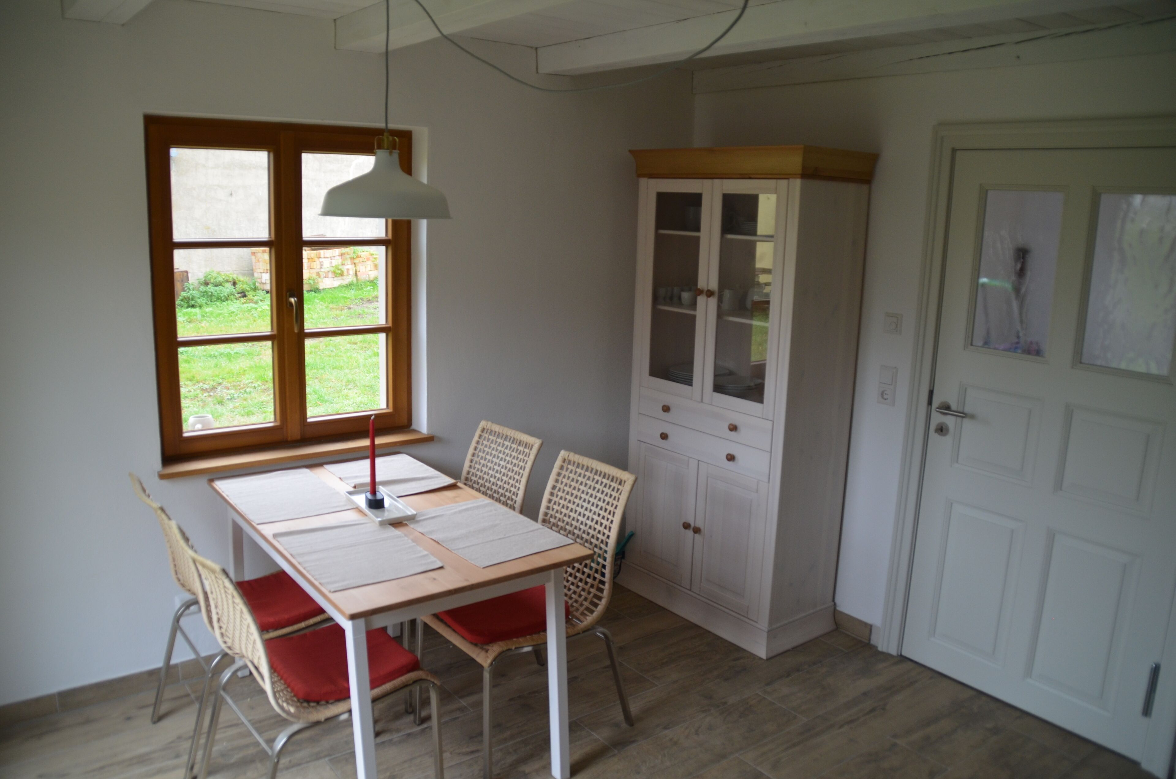 Una habitación con una mesa de comedor, sillas, un armario, una ventana y una puerta.