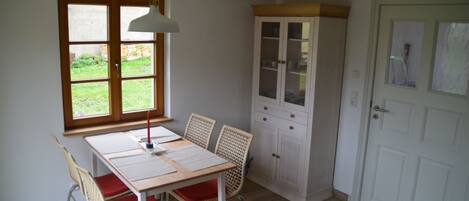 Una habitación con una mesa de comedor, sillas, un armario, una ventana y una puerta.