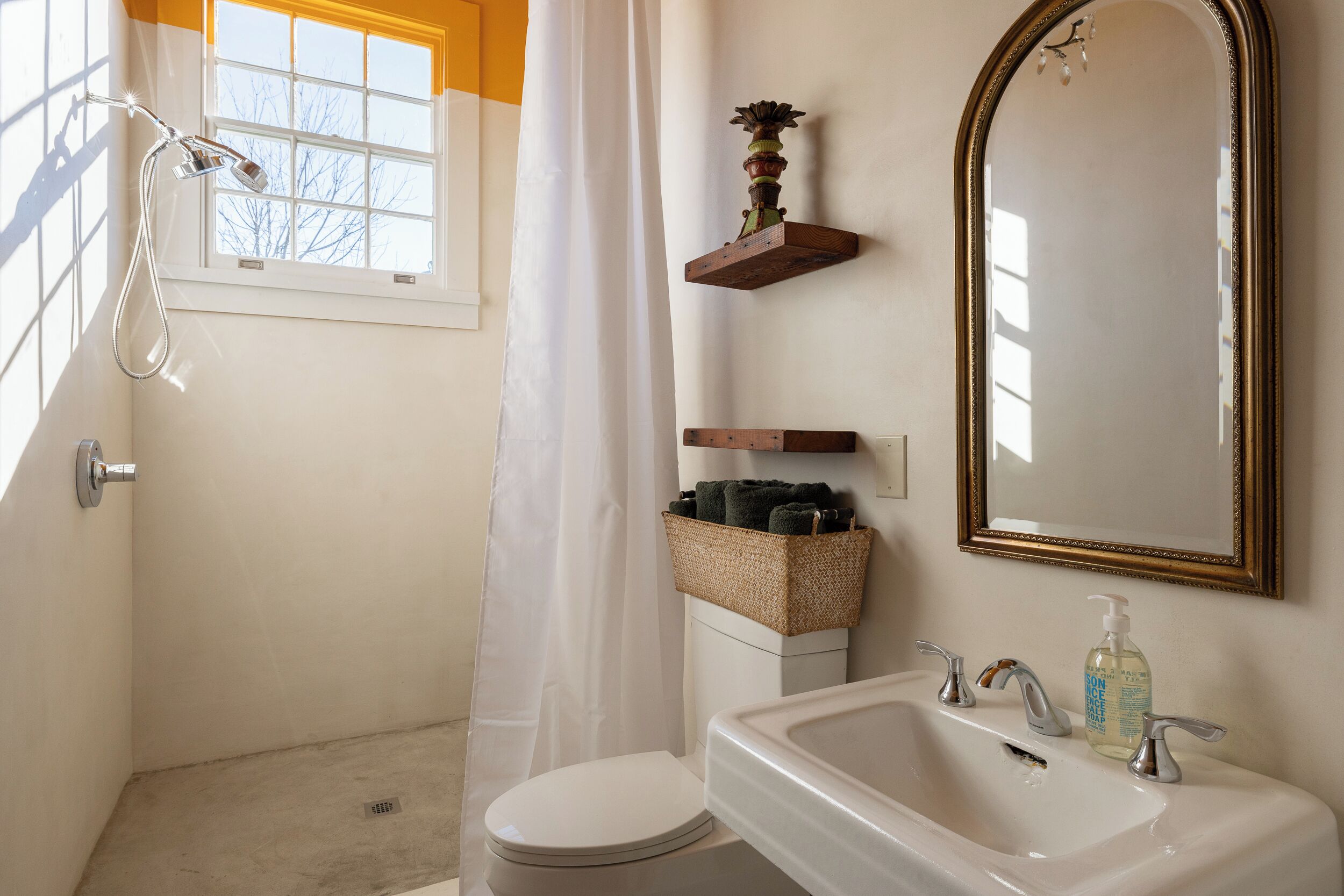 A bathroom with a shower, toilet, sink, and a mirror.