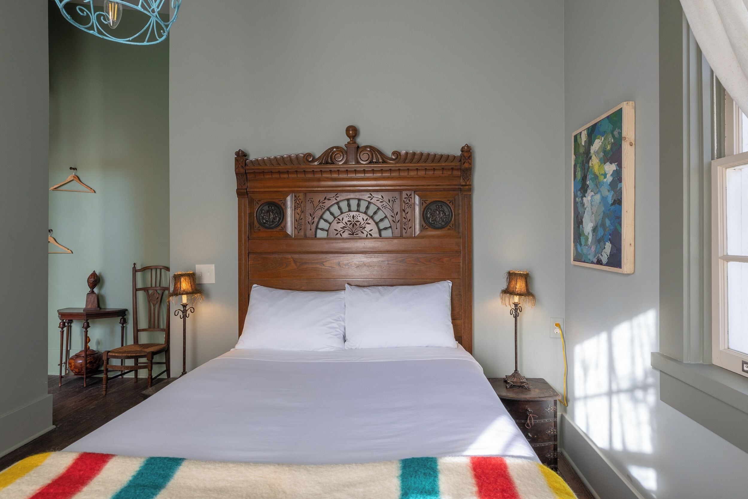 A neatly made bed with a wooden headboard, two bedside lamps, and a colorful striped rug.