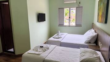 Habitació d'hotel amb dos llits, una finestra amb persianes, un aire condicionat i un quadre a la paret.