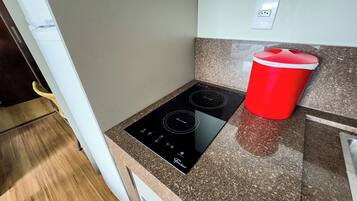 Una cocina con tope de inducción negro, un recipiente rojo y encimeras de granito.