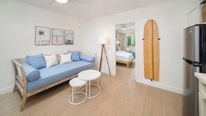 Una sala de estar moderna con un sofá azul, una mesa de centro blanca y una tabla de surf montada en la pared.