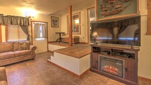 Een woonkamer met een open haard, een televisie, een bank en een houten salontafel.
