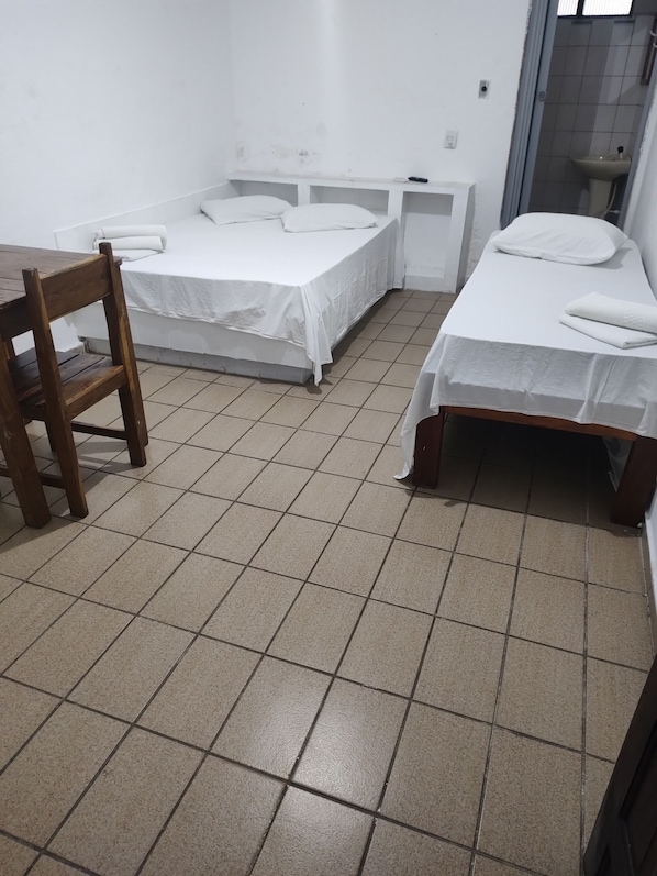 A small, clean room with two single beds, a wooden chair, and a small table. - pousada mare mansa (Maceio)