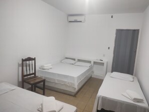 Ein Zimmer mit zwei Einzelbetten, einem Holzstuhl, einem kleinen Tisch und einer Tür.