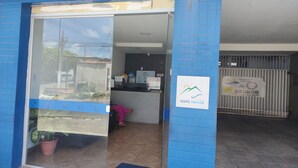 L'ingresso di un edificio con una reception, una parete rivestita di piastrelle blu e un cartello che indica 'POUSADA MARÉ MANSA'.