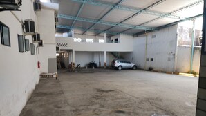 Un'ampia area di parcheggio interna, con pavimento in cemento, un'auto argentata parcheggiata al centro e un edificio con tetto in metallo e pareti bianche.