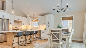 Una cocina moderna con armarios blancos, un refrigerador de acero inoxidable y una isla central con taburetes de bar.