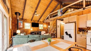 A cozy cabin interior with a dining area, kitchen, and a loft bedroom. - 2 Mi to Conway: Cozy Cabin w/ Grill & Yard! (Center Conway)