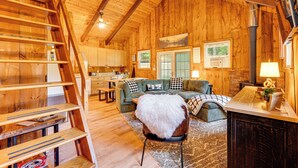 A wooden cabin interior with a loft bedroom, a dining area, and a living room with a fireplace. - 2 Mi to Conway: Cozy Cabin w/ Grill & Yard! (Center Conway)