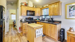 A kitchen with wooden cabinets, a microwave, stove, sink, and a small refrigerator. - Remote Workers Welcome: Tiny Home in Port Angeles! (Port Angeles)