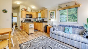 A compact kitchen with wooden cabinets, a dining table, and a sofa. - Remote Workers Welcome: Tiny Home in Port Angeles! (Port Angeles)