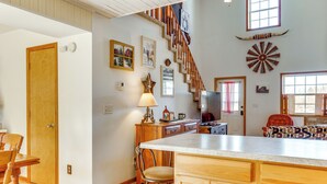 A spacious kitchen with a large island, wooden cabinets, and a staircase leading to an upper level. - 'Red Barn Getaway' Chillicothe Countryside Home (Chillicothe)