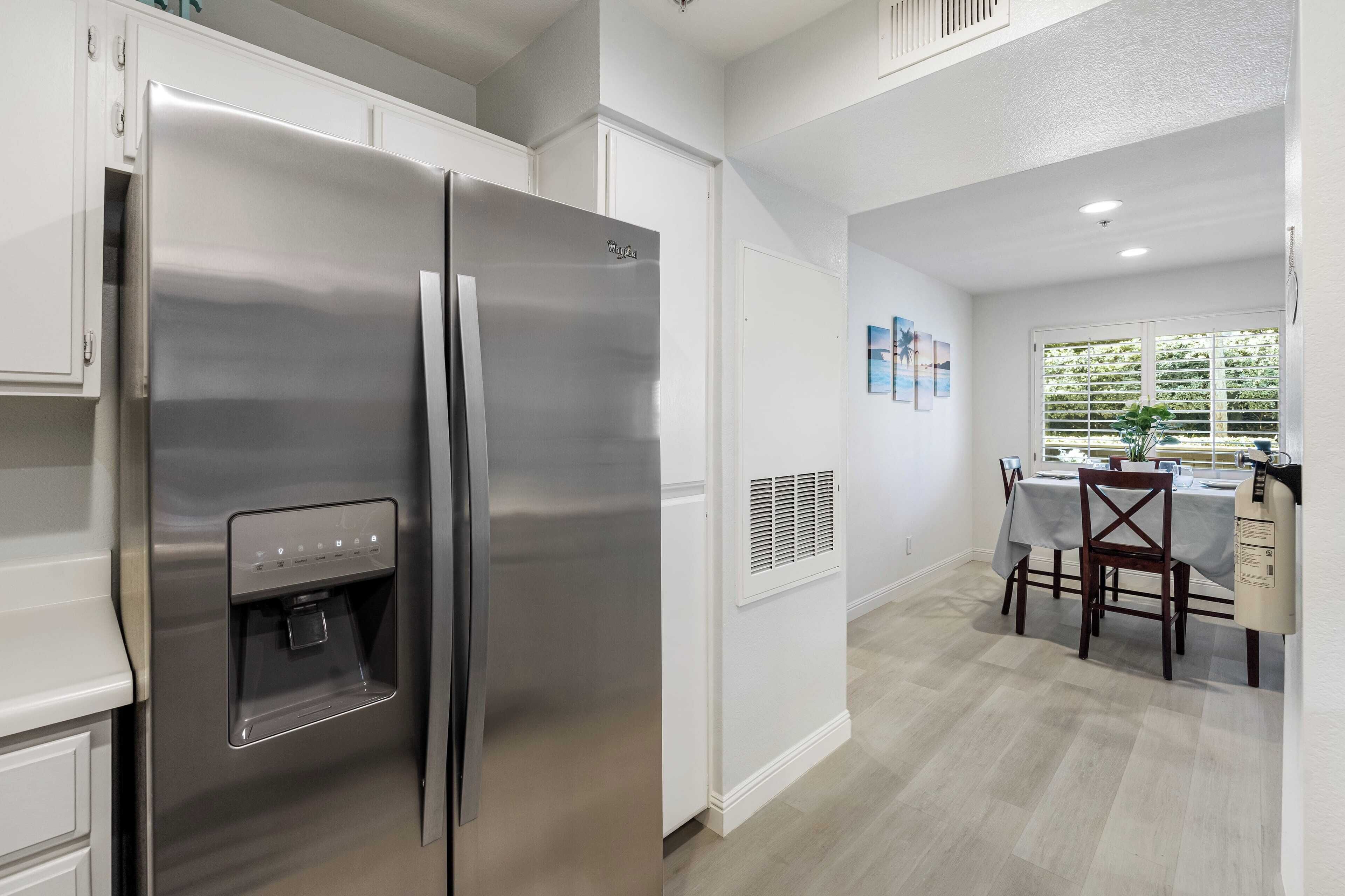 Una cocina moderna con un refrigerador de acero inoxidable, dispensador de agua integrado y un comedor con mesa y sillas.