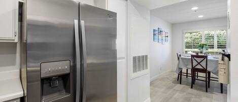Una cocina moderna con un refrigerador de acero inoxidable, dispensador de agua integrado y un comedor con mesa y sillas.