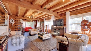 A cozy log cabin interior with a fireplace, plush seating, and a television. - < 4 Mi to Boat Ramp & Mickler Beach: Unique Cabin (Ponte Vedra Beach)