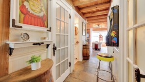 A hallway with wooden beams, a white door with glass panels, a potted plant, and a stool. - < 4 Mi to Boat Ramp & Mickler Beach: Unique Cabin (Ponte Vedra Beach)