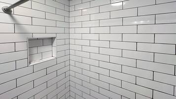 A corner of a room with white tiled walls and a metal towel rack.