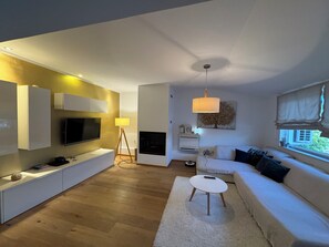 A modern living room with a flat-screen TV, a sofa, a coffee table, and a floor lamp.